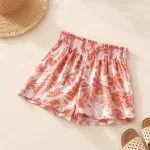 Coral floral shorts laid flat beside a straw hat and sandals