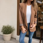 Woman wearing a camel blazer with leopard-pattern cuffs over a white top and blue jeans