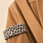 Close-up of a camel blazer showing a leopard-pattern turned cuff and broad lapel