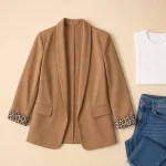 Camel blazer with patterned cuffs laid flat beside a white T-shirt and blue jeans