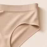 Nahaufnahme der beigefarbenen Unterhose mit breitem Bund, glattem Stoff und geschwungenem Beinabschluss