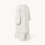 Rear angled view of the off-white top and shorts showing loose sleeves and a long top hem