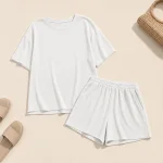 Off-white ribbed top and shorts laid flat beside sandals and a woven bag