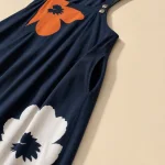 Nahaufnahme der orange-weißen Blumen, Schulterknöpfe und Seitentasche eines marineblauen Jumpsuits