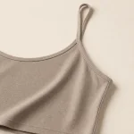 Close-up of a taupe camisole's thin strap, stitched neckline and fine ribbed texture