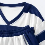 Dettaglio del completo a righe con bordo blu navy dello scollo a V, cintura arricciata e bordo della tasca