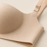 Close-up of a beige bra showing a smooth cup, strap adjuster and folded lower edge