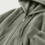Nahaufnahme des grünen Hoodies mit Reißverschluss, Kordeln, Bündchen und Vordertasche