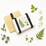 Presse à plantes en bois ouverte avec feuilles et fleurs sur feuilles blanches, près de la planche supérieure retirée