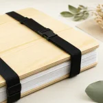 Gros plan sur une presse à plantes montrant le grain du bois, des couches blanches empilées et une sangle noire à boucle