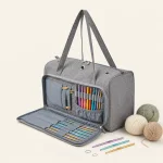 Borsa grigia per filati con pannello frontale aperto per utensili, che mostra uncinetti accanto a gomitoli