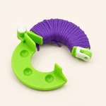 A green curved maker arm with purple yarn wrapped around it, showing the winding area and white clasp.