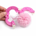 A pink yarn pom-pom being released from the opened maker after its center is tied.