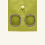 Gros plan sur le sac à foin vert montrant deux ouvertures bordées de gris et un petit pompon crème