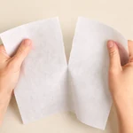 Hands gently separating white tear-away backing