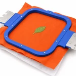 White backing beneath orange woven fabric in an embroidery hoop