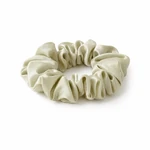 Un chouchou vert pâle disposé en anneau de tissu froncé sur fond blanc