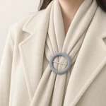 A scarf arranged through a fabric-covered round slide buckle on a coat.