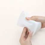 Hands bending a translucent square coaster mold to show its flexible walls