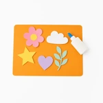Orange silicone craft mat with paper flowers, a star, a heart and a glue bottle