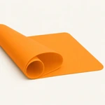 Side view of an orange flexible silicone mat partly rolled for storage
