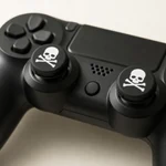 Two white skull-print caps fitted over a black game controller’s thumbsticks