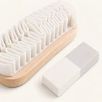 Close-up of the brush showing rows of white folded fins and its wooden base beside the cleaning eraser