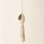 Side three-quarter view of a beige macrame plant hanger with a woven basket and fringe.
