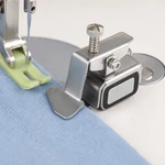 PINSEAM magnetic seam guide positioned at a fabric edge on a sewing machine needle plate