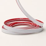 White PVC wall trim coiled with the red adhesive release liner visible inside.