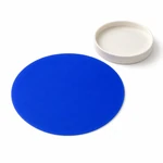 A round silicone gripper pad shown beside a plain jar lid, with its circular surface visible.