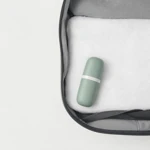 Estuche verde cerrado dentro de una bolsa de viaje abierta