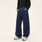Model mit dunkelblauer Jeans mit weitem Bein, Händen in den Vordertaschen, schwarzem Oberteil und hellgrauen Sneakern.