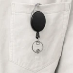 Black badge reel clipped to plain fabric by its carabiner