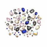 Representative spread of faceted glass sew-on rhinestones in assorted visible colors and shapes on white.