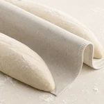 Shaped bread dough resting between folds of the beige linen couche